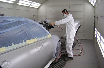 Technician spray-painting a panel in the Garmat downdraft bake paint booth